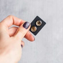 Handmade black stud earrings with vintage watch parts embedded inside.