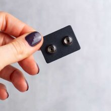 Silver minimalist steampunk earrings on card held in hand, 6mm